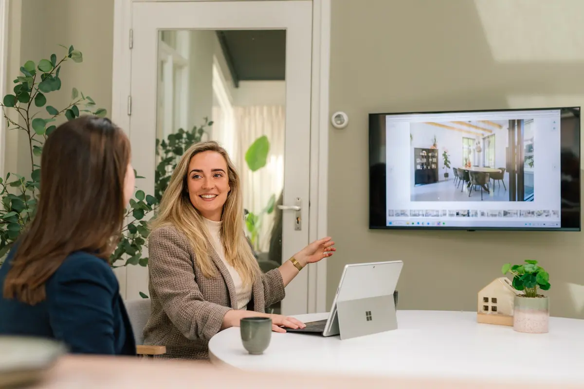Twee collega's van Makelaardij Faber in gesprek met een klant aan tafel, met de woning op een scherm