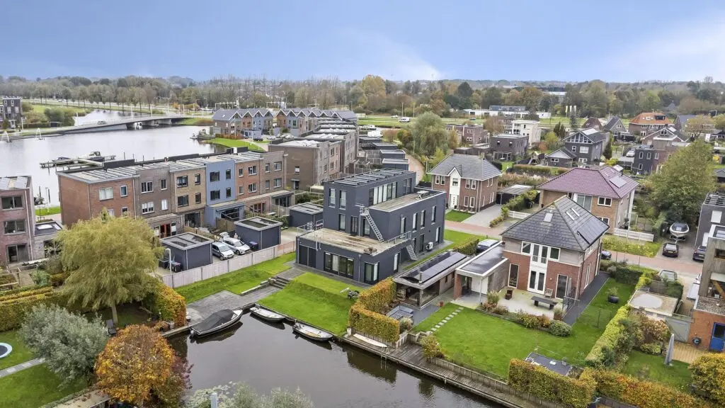 Luchtfoto van een woonwijk aan het water met ruime vrijstaande en geschakelde woningen